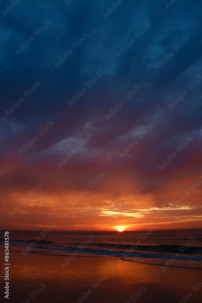 Fototapeta premium A beautiful combination of clouds and sun on a Florida beach during sunrise in a portrait shot