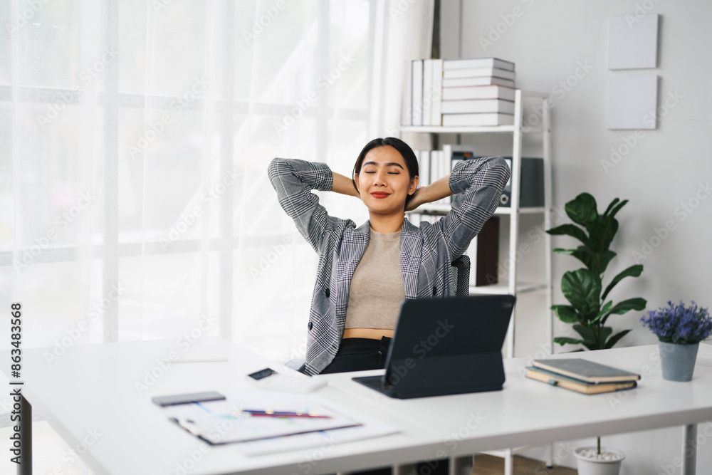 Confident Asian Business Woman Relaxing at Modern Office Desk with Laptop and Documents Confident Asian Business Woman Relaxing at Modern Office Desk with Laptop and Documents