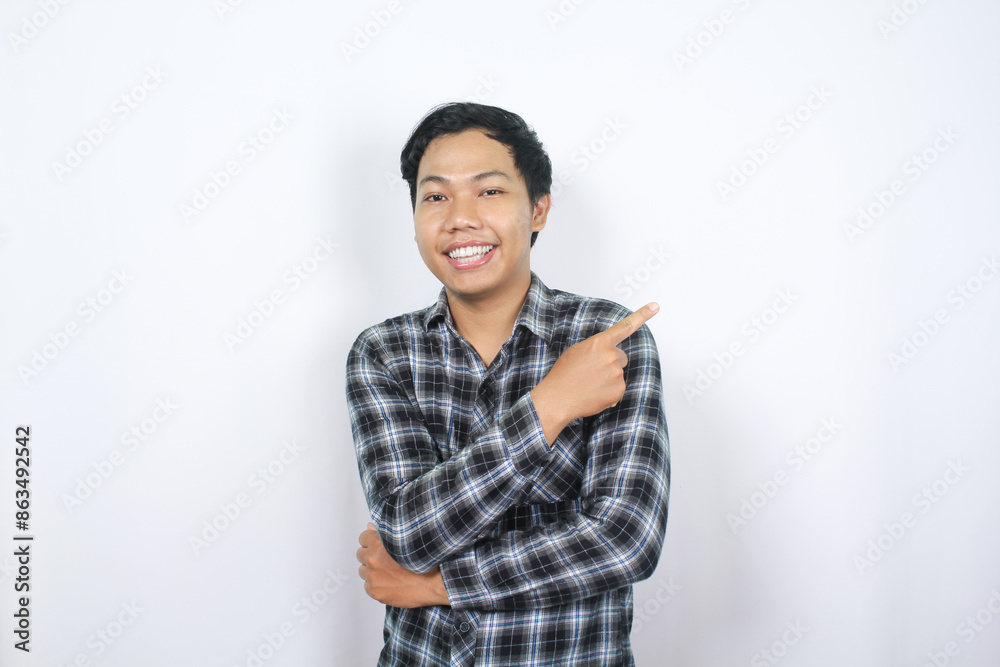 smiling asian man pointing finger to aside with folded arm isolated smiling asian man pointing finger to aside with folded arm isolated