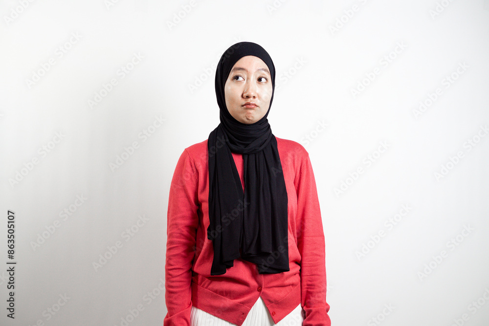 Young Asian woman in hijab with pink sweeter. standing pose while thinking isolated white blank background. Young Asian woman in hijab with pink sweeter. standing pose while thinking isolated white blank background.