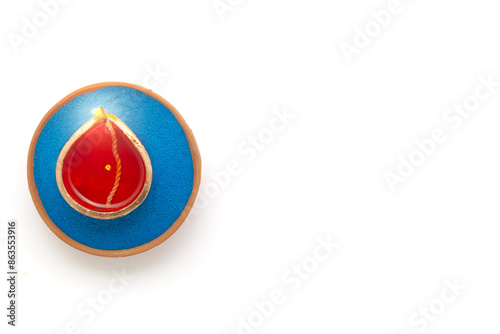 A top view of a Diwali diya (an earthen oil lamp) placed on blue Rangoli Powder, isolated on a white background. photo