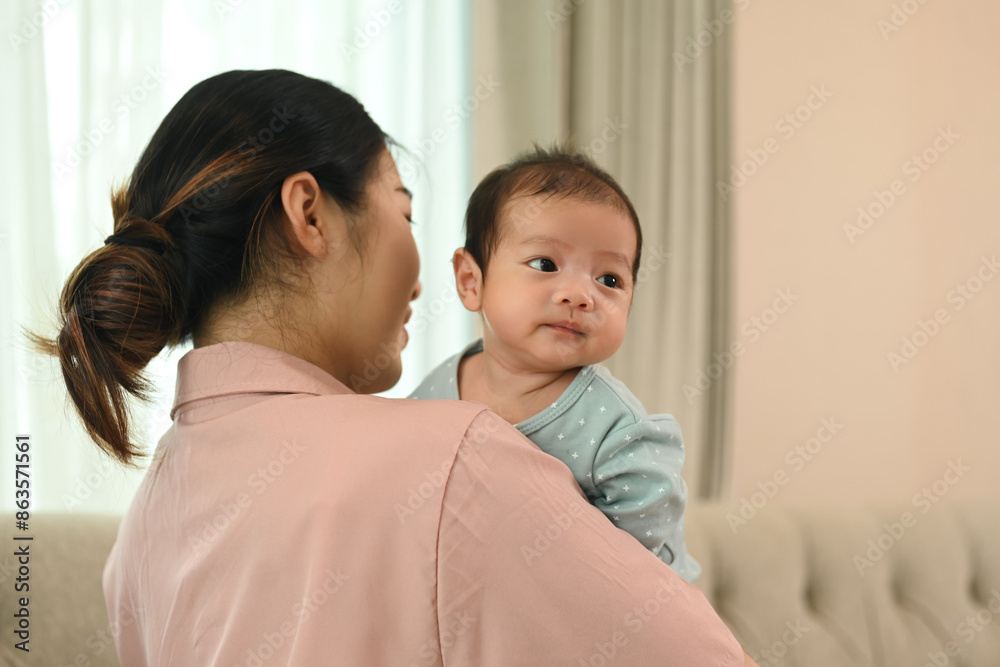 Beautiful young Asian mother carrying newborn baby in living room. Love moment and mother's day concept Beautiful young Asian mother carrying newborn baby in living room. Love moment and mother's day concept