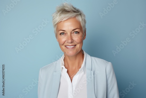 Portrait of smiling senior businesswoman with short hair against blue background