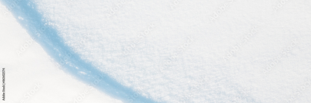 Obraz premium Wide panoramic winter background with snowy ground. Natural snow texture. Wind sculpted patterns on snow surface. Closeup top view with copy space.