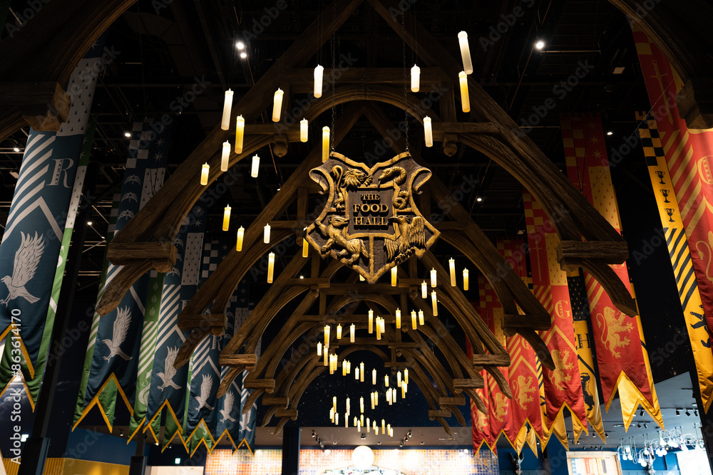 Obraz premium JAPAN - Nov 13, 2023: Hogwarts canteen with the food hall logo banner featuring floating candles and Slytherin and Gryffindor flag hanging at Warner Bros Studio Tour Tokyo, The Making of Harry Potter
