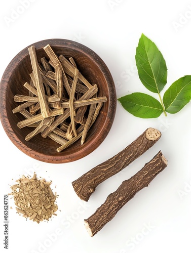 Top view of licorice root in a wooden bowl with powdered licorice and green leaves on a white background.