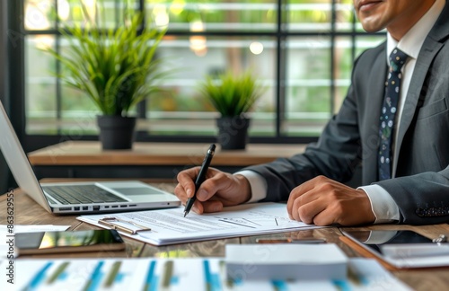 Businessman Writing in Notebook at Desk in Office