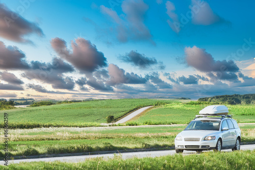 Car with roofbox driving through scenic landscape photo