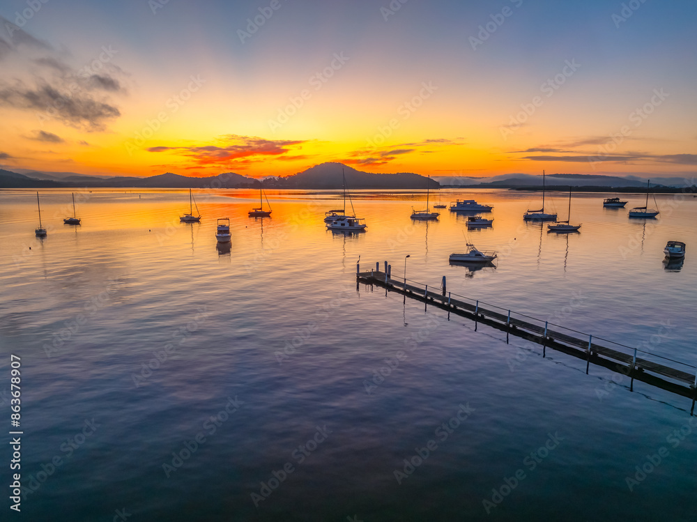 Fototapeta premium Sunrise over the calm water with boats and reflections
