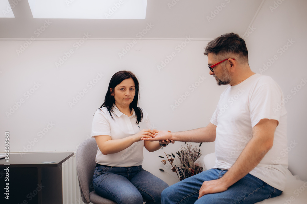 Physical therapist applying kinesio tape to the patient's hand Physical therapist applying kinesio tape to the patient's hand