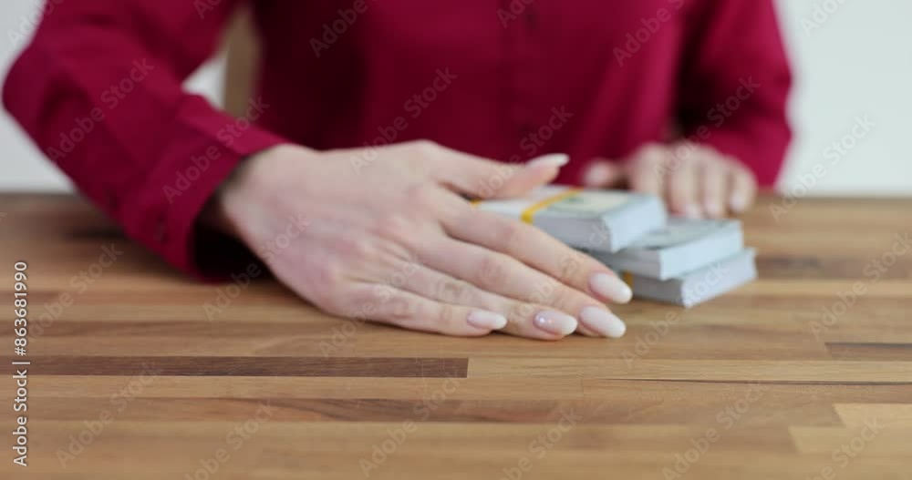 Employee takes stacks of money from table in office Employee takes stacks of money from table in office
