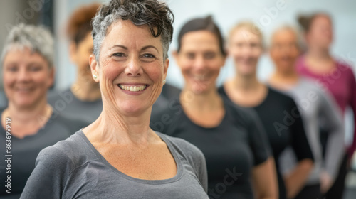 Smiling earopean adult female trainer stands against the background of a group of people © SERGEY