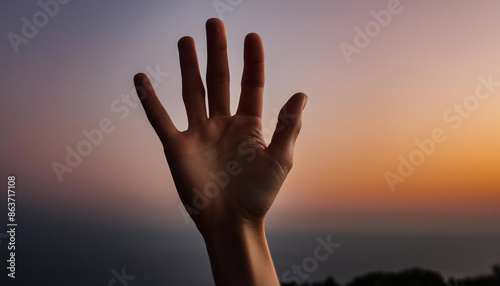 Silhouette raised hand fingers spread against sunset mountain backdrop, symbolizing hope, reaching out, help signal.