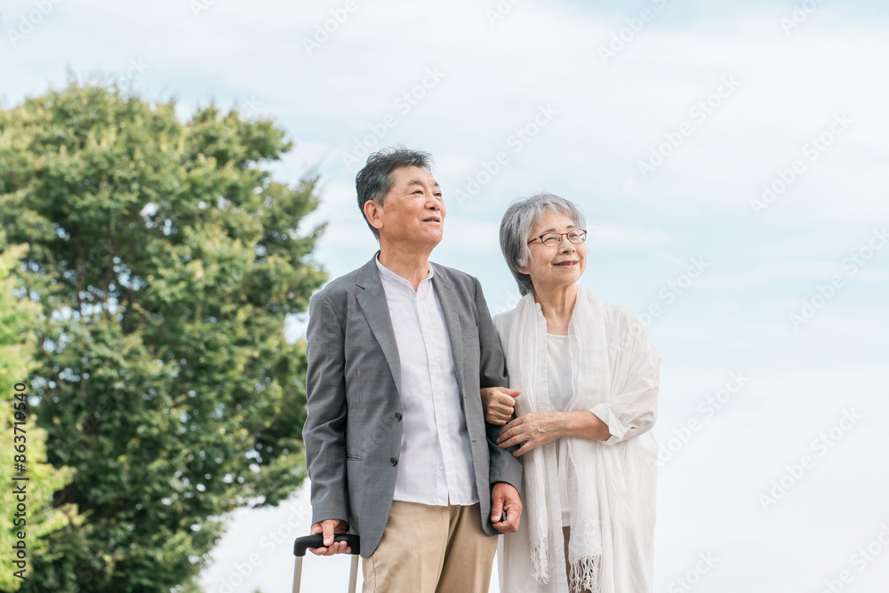 スーツケースを持って旅行する高齢者夫婦（シニアライフ・アクティブシニア）
