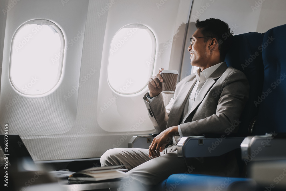 Asian businessman enjoying enjoys a coffee comfortable flight while sitting in the airplane cabin, Passengers near the window.
