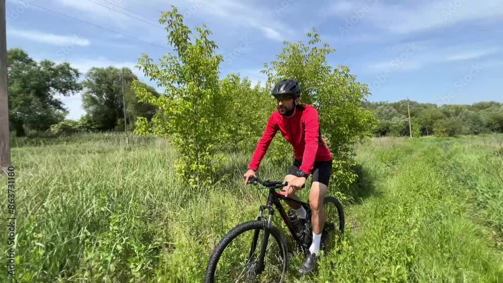 Man cycling through lush green fields, enjoying a peaceful countryside journey under clear blue skies Man cycling through lush green fields, enjoying a peaceful countryside journey under clear blue skies