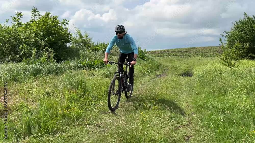 Explore a lush green field on a mountain bike trail. Ideal for fitness, adventure, and nature themed projects Explore a lush green field on a mountain bike trail. Ideal for fitness, adventure, and nature themed projects
