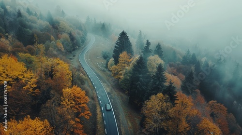 Car driving on winding mountain road  aerial view of coniferous forest in autumn fog