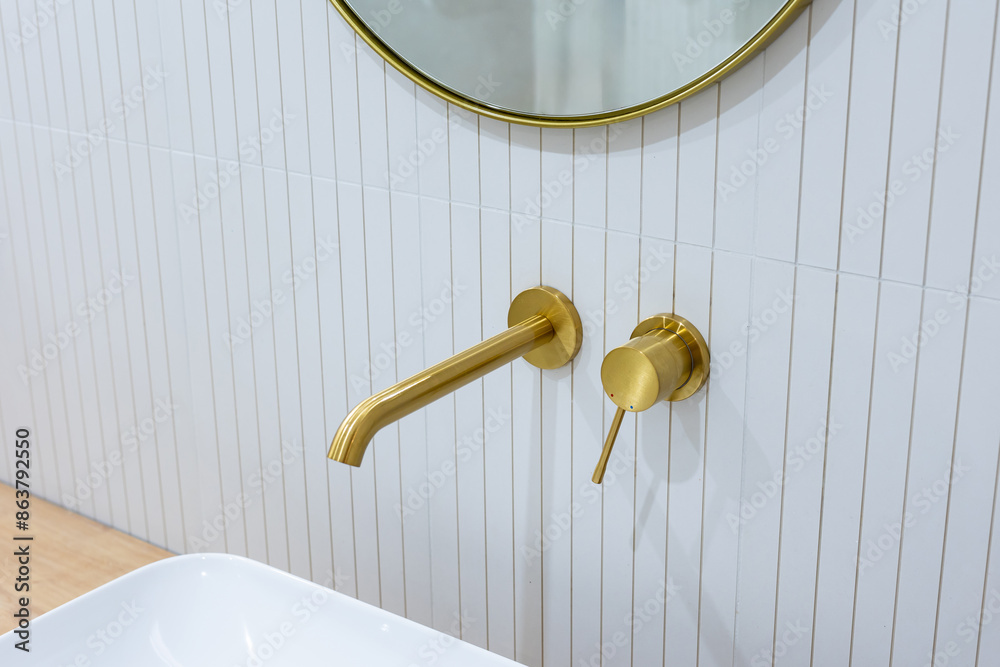 Bronze bathroom water tap in a bathroom finished with white tiles. Minimalist bathroom finish. Photographed in natural light.