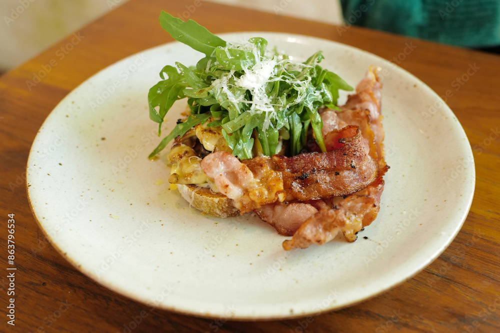 Close up plate of bacon and rocket salad on toast served with sausage Close up plate of bacon and rocket salad on toast served with sausage