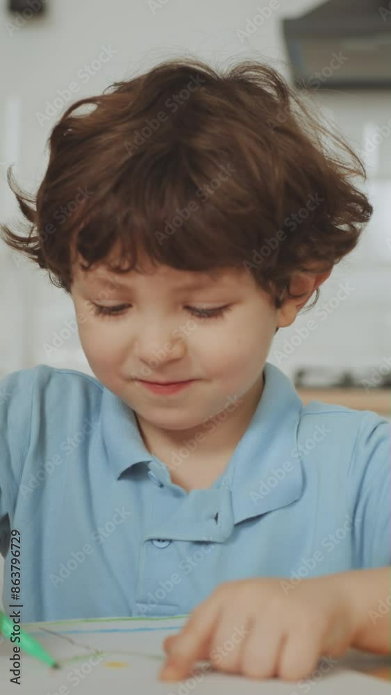 Vertical screen: Young boy focused on drawing with crayons and markers at table. Concept of creative activities and early childhood education. Learning and creativity at home Vertical screen: Young boy focused on drawing with crayons and markers at table. Concept of creative activities and early childhood education. Learning and creativity at home