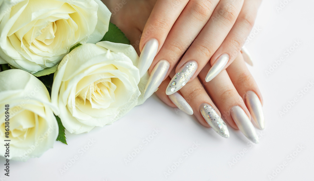 Fototapeta premium Female Hands on a white background with beautiful pearl manicure and white roses.