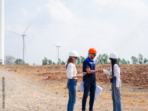 Group of engineers and architects working on the basis of a wind turbine Inspect the structure with the wind turbine in the background.