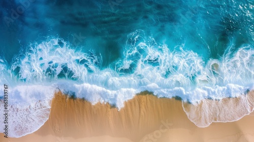 A top view of waves crashing onto a sandy beach.