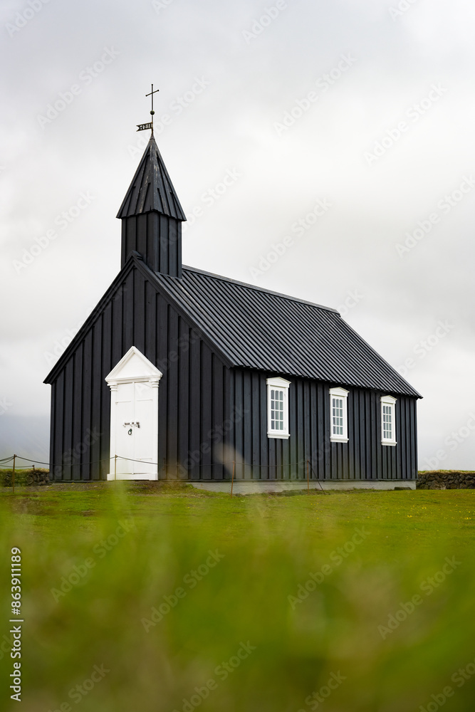 Stunning view of the black church of Budir with defocused grass in the foreground. Búðakirkja is a small wooden church located on the south side of Snæfellsnes, Iceland.