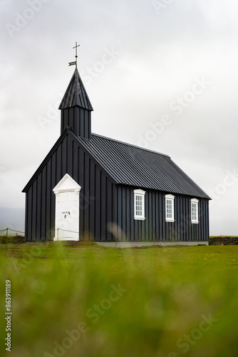 Obraz na płótnie Stunning view of the black church of Budir with defocused grass in the foreground. Búðakirkja is a small wooden church located on the south side of Snæfellsnes, Iceland. w salonie