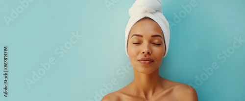 Studio portrait of clean beautiful woman drying off hair in towel turban, blue background