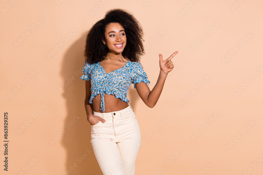 Photo of charming positive woman wear blue top pointing empty space isolated beige color background