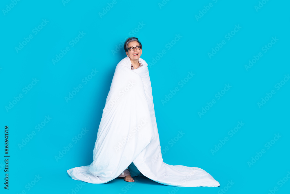 Photo of dreamy cute nice retired woman wrapped cozy blanket look empty space isolated on blue color background Photo of dreamy cute nice retired woman wrapped cozy blanket look empty space isolated on blue color background