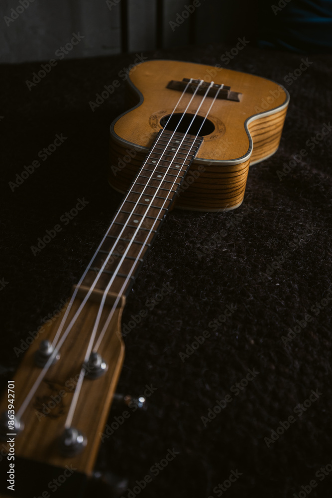A Wooden Ukulele stands out on a dark fabric backdrop, blending art and music harmoniously A Wooden Ukulele stands out on a dark fabric backdrop, blending art and music harmoniously