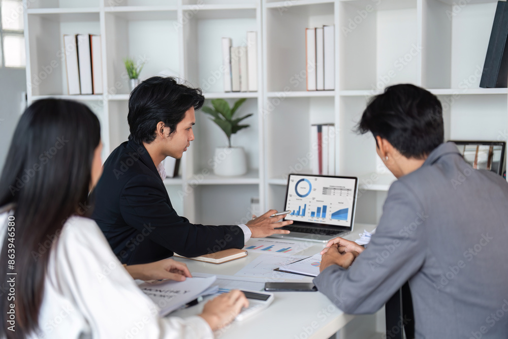 Business Team Collaborating in Modern Office, Analyzing Data on Laptop, and Sharing Ideas for Project Development Business Team Collaborating in Modern Office, Analyzing Data on Laptop, and Sharing Ideas for Project Development