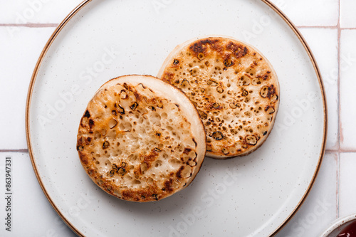 Hot Toasted Crumpets with on a plate with strawberry jam nearby. Perfect tasty breakfast