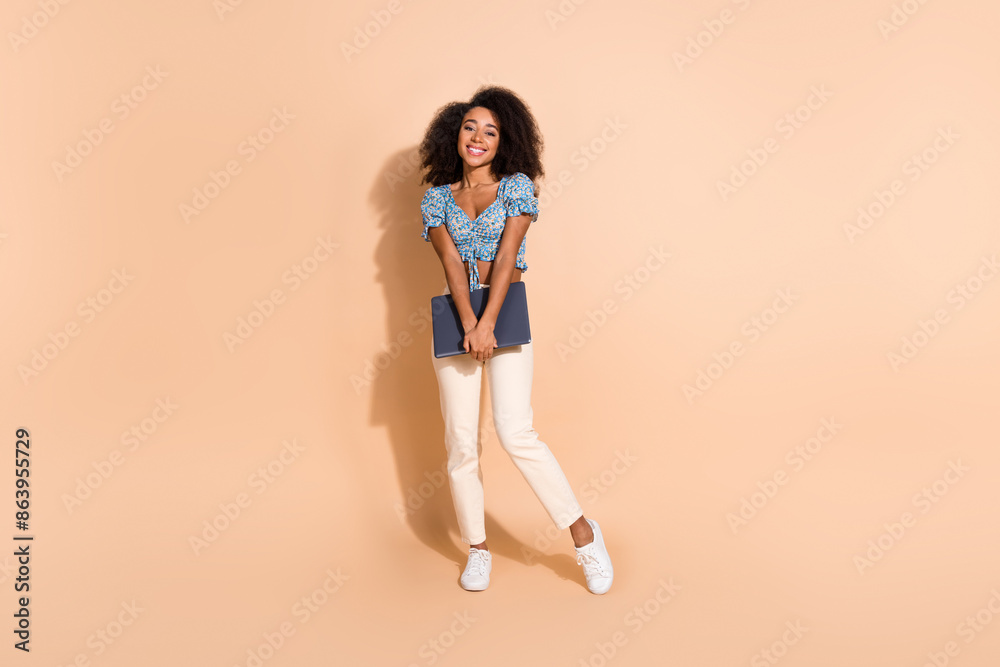 Full length photo of adorable lovely girl wear blue top holding modern device empty space isolated beige color background Full length photo of adorable lovely girl wear blue top holding modern device empty space isolated beige color background