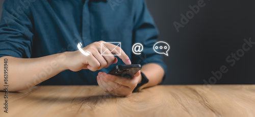 Communication and Contact us or Customer support hotline people connect. Businessman Hand using a laptop and touching on virtual screen contact icons, email and address, live chat with internet wifi.