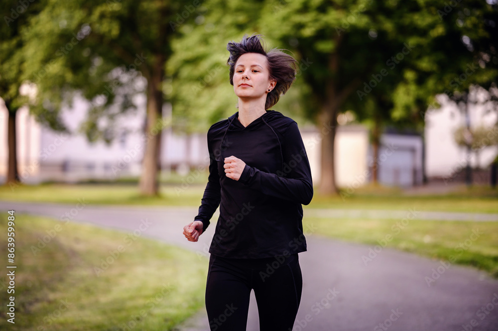 A young woman in athletic wear jogging on a forest trail, surrounded by lush green trees. Capturing a healthy lifestyle and outdoor fitness. A young woman in athletic wear jogging on a forest trail, surrounded by lush green trees. Capturing a healthy lifestyle and outdoor fitness.