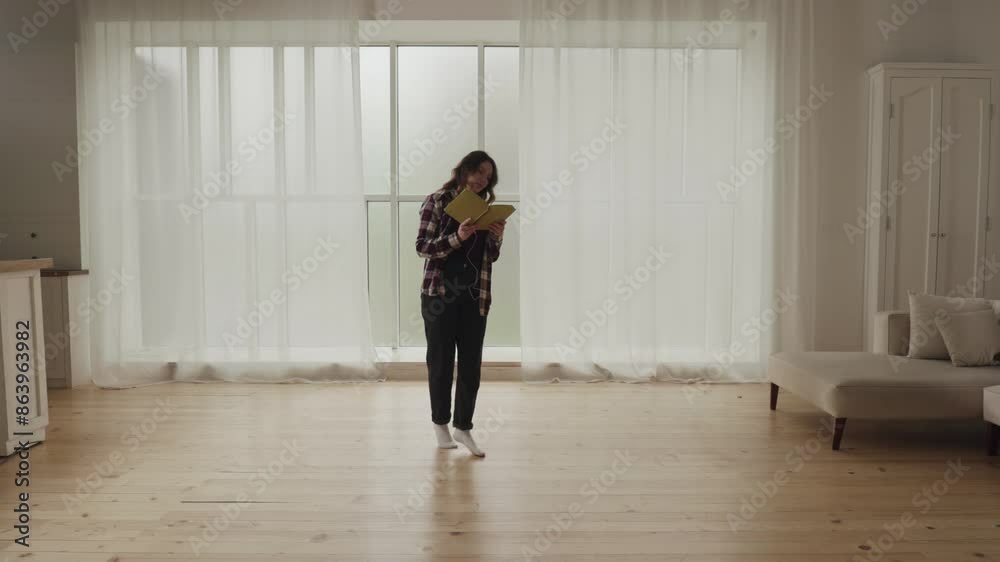 A woman is peacefully reading a book in a contemporary living room, enjoying a quiet moment A woman is peacefully reading a book in a contemporary living room, enjoying a quiet moment
