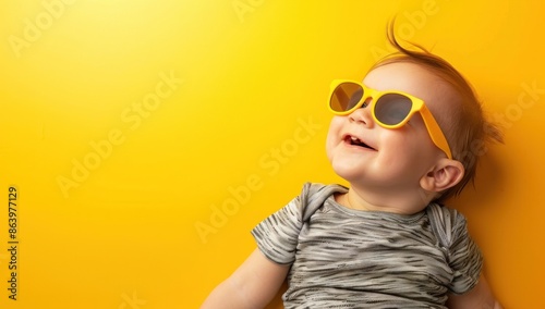 Happy Baby in Sunglasses Against Yellow Background photo
