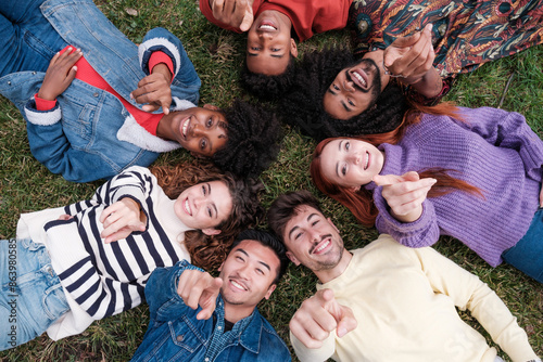 Overhead view of a group of young people pointing the way while lying on the ground. Concept: lifestyle