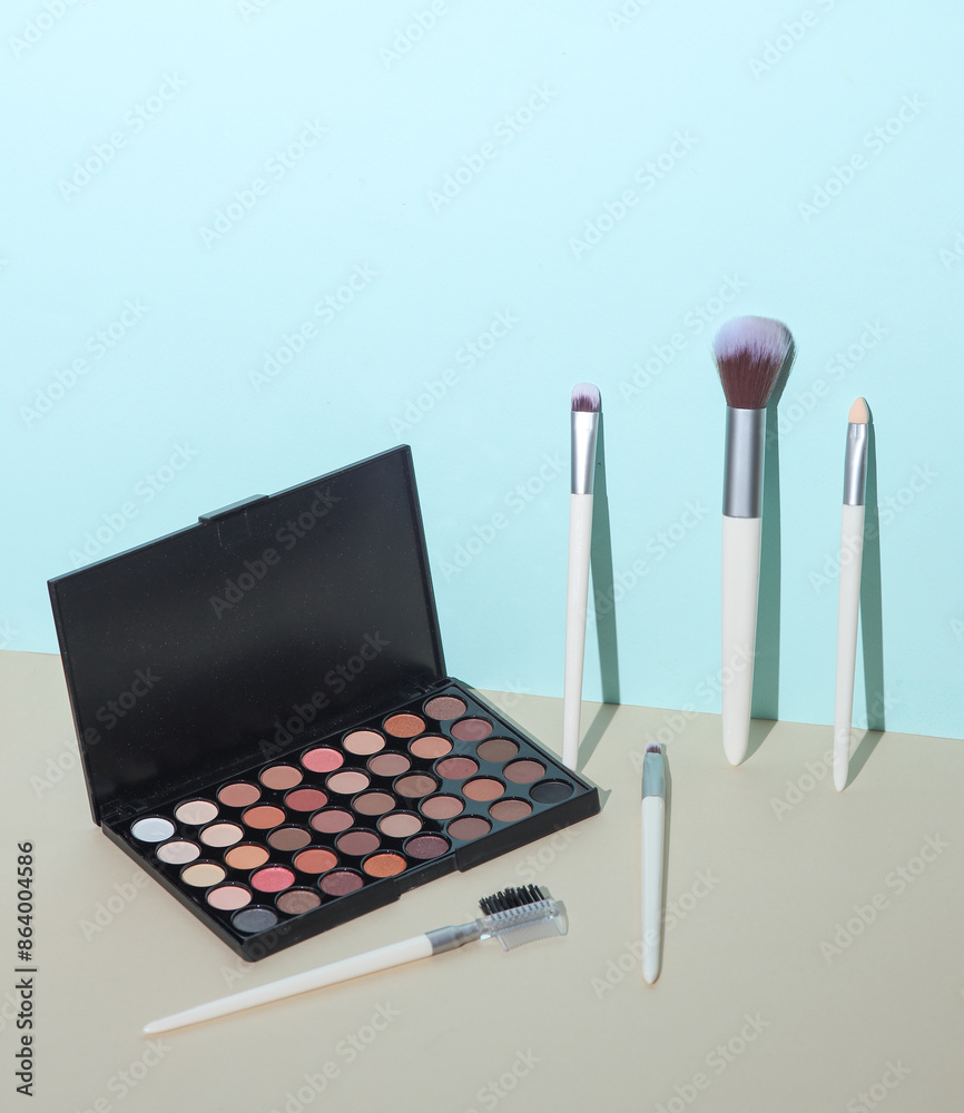 Set of makeup brushes and eye shadows palette on a blue beige background Set of makeup brushes and eye shadows palette on a blue beige background