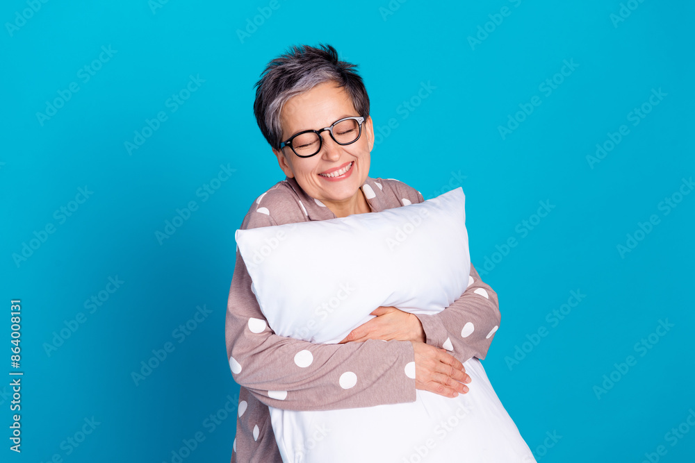 Photo of good mood pretty lovely senior woman wear trendy pajama hold soft pillow isolated on blue color background Photo of good mood pretty lovely senior woman wear trendy pajama hold soft pillow isolated on blue color background