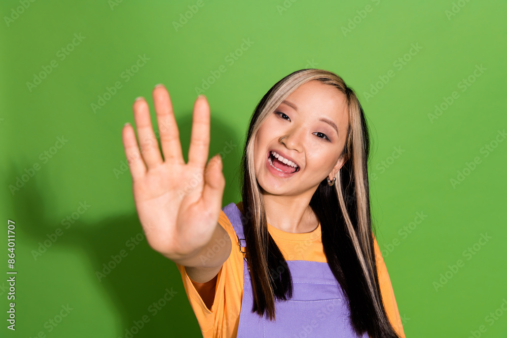Photo portrait of attractive young woman wave hand dressed stylish violet yellow clothes isolated on green color background Photo portrait of attractive young woman wave hand dressed stylish violet yellow clothes isolated on green color background