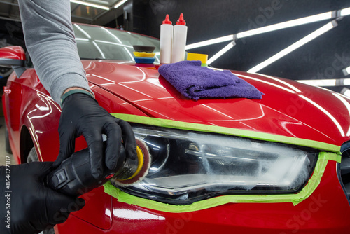 Headlight polishing. Adhesive tape on car headlights. Detailing car outside.