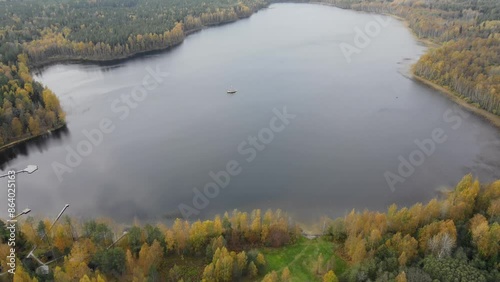 Drone flying over a beautiful lake surrounded by forest in autumn. Recreation in the forest by the lake. High quality 4k footage