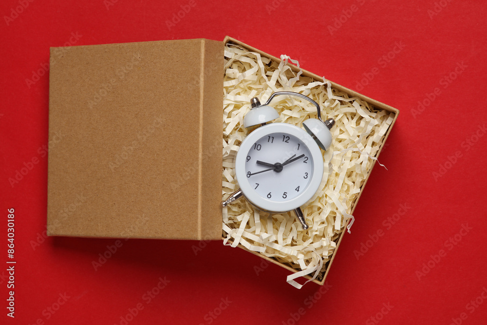 Alarm clock in craft box with filler on red background. Product packing Alarm clock in craft box with filler on red background. Product packing