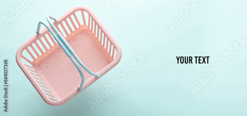 Plastic miniature supermarket grocery basket on blue pastel background. Copy space