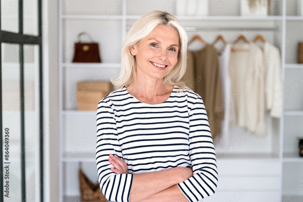 Smiling middle aged woman standing in front of open wardrobe Smiling middle aged woman standing in front of open wardrobe